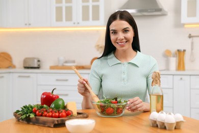 Photo of Happy woman cooking salad at table in kitchen. Keto diet