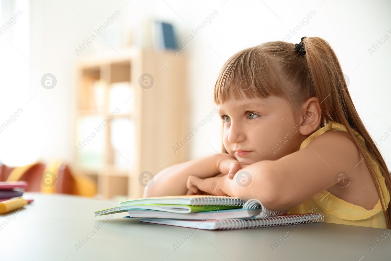 Photo of Cute little child sitting at desk in classroom. Elementary school