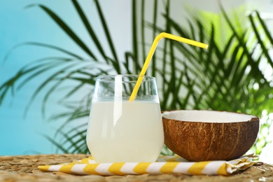 Photo of Composition with glass of coconut water on wicker table against blue background