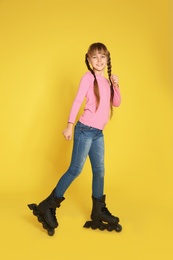 Girl with inline roller skates on color background