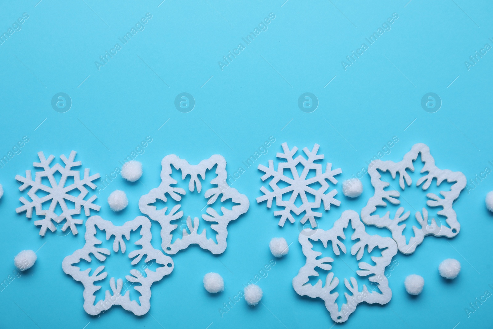 Photo of Beautiful decorative snowflakes on light blue background, flat lay. Space for text