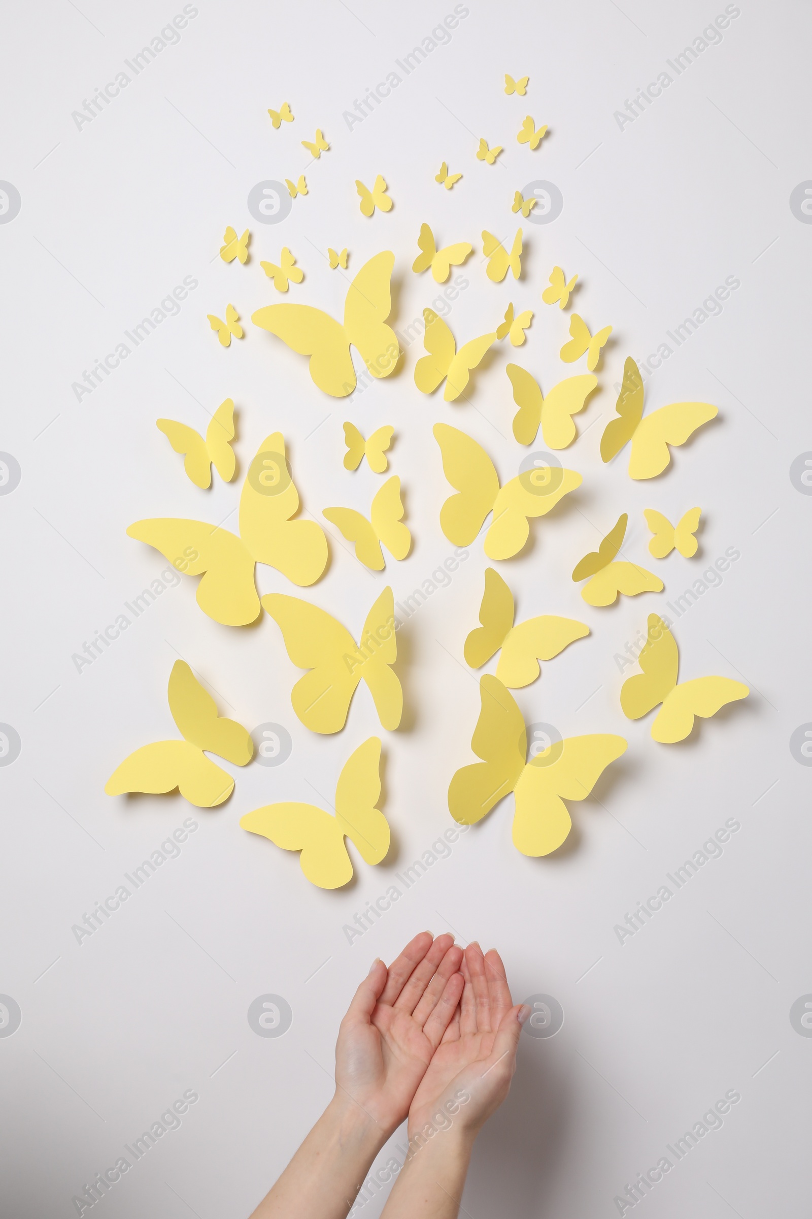 Photo of Woman with yellow paper butterflies on white background, top view