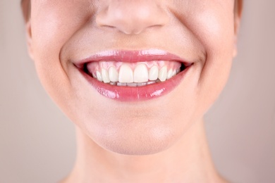 Photo of Young woman with healthy teeth smiling on color background, closeup