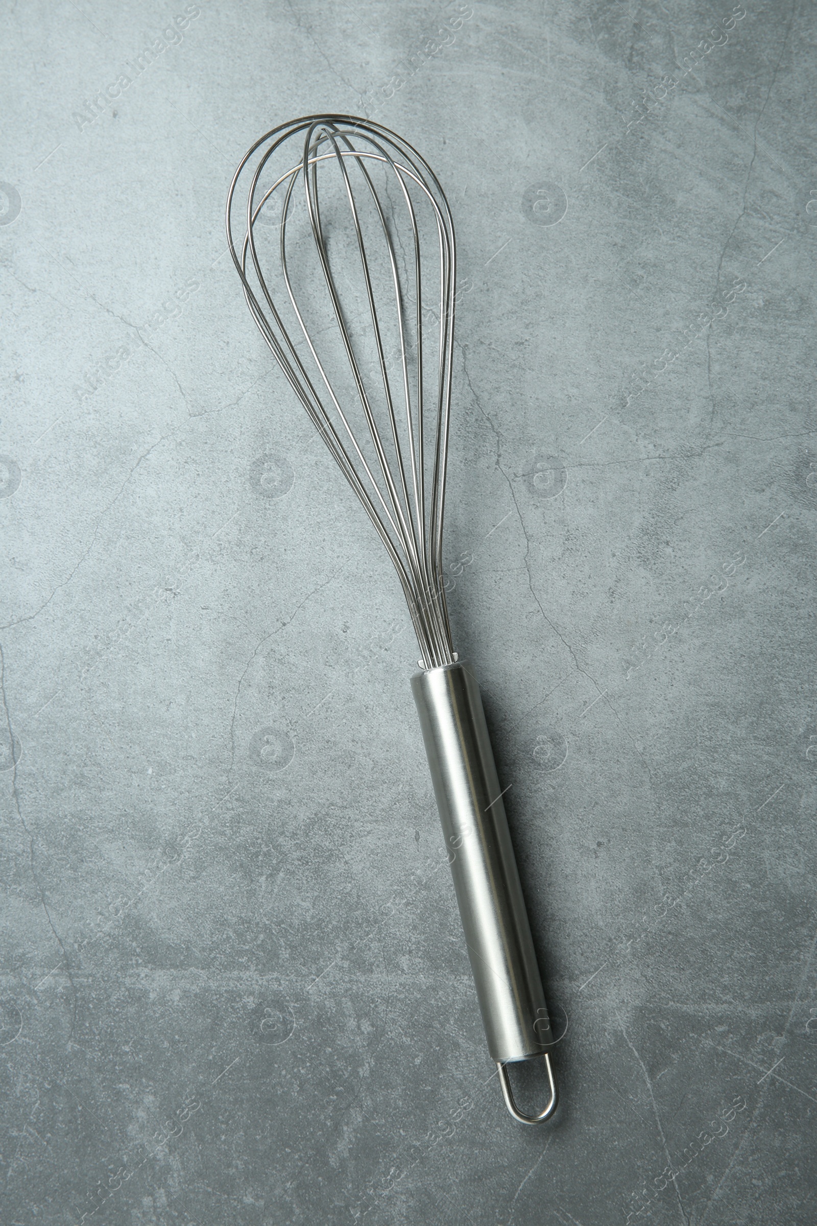 Photo of Metal whisk on gray table, top view