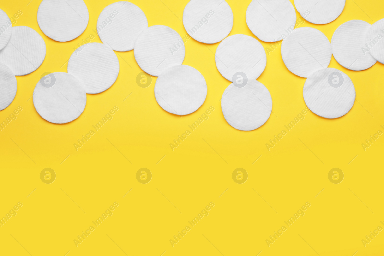 Photo of Soft clean cotton pads on yellow background, flat lay. Space for text