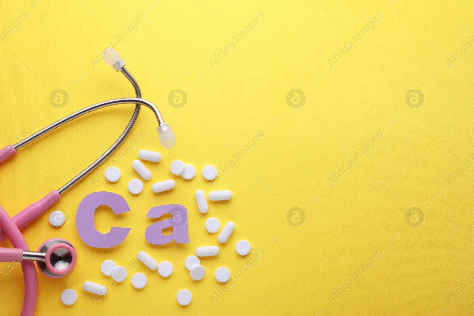 Photo of Stethoscope, pills and calcium symbol made of purple letters on yellow background, flat lay. Space for text