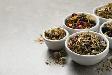 Photo of Different dry aromatic teas on light grey table, space for text