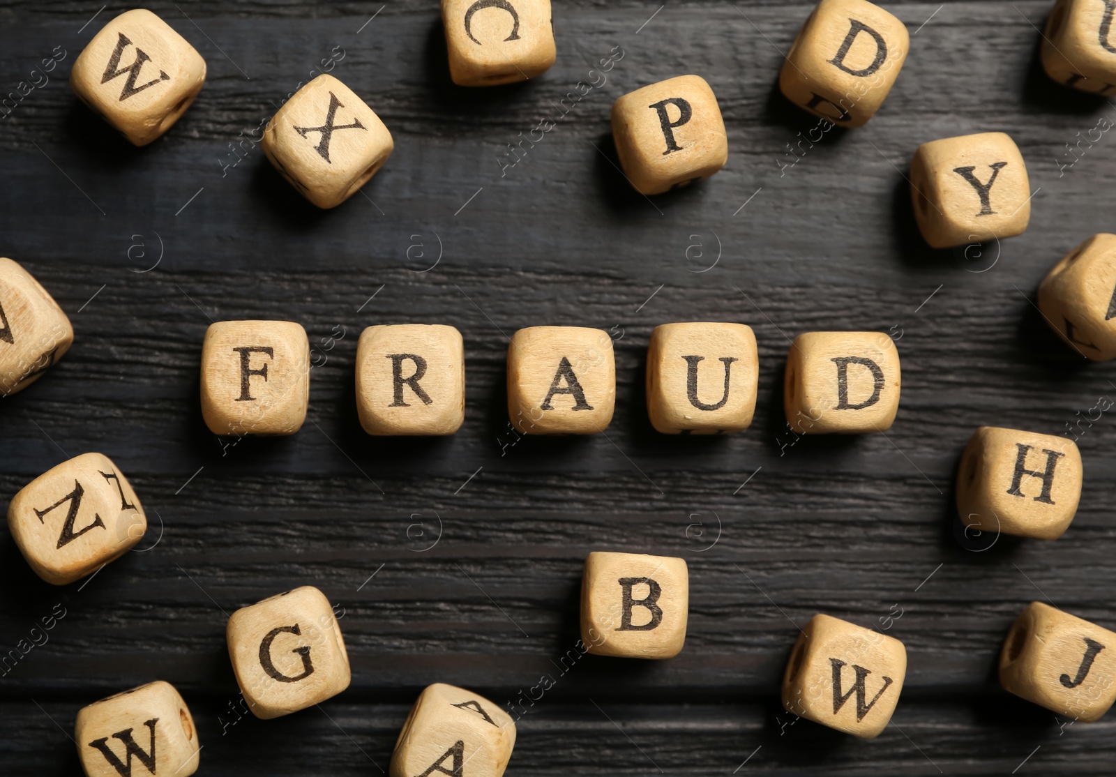 Photo of Word Fraud of cubes with letters on black wooden background, flat lay