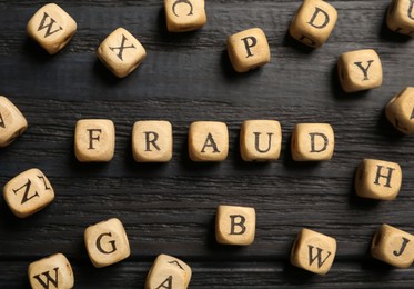 Word Fraud of cubes with letters on black wooden background, flat lay