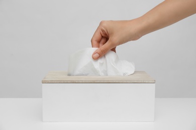 Photo of Woman taking paper tissue from holder on light background, closeup