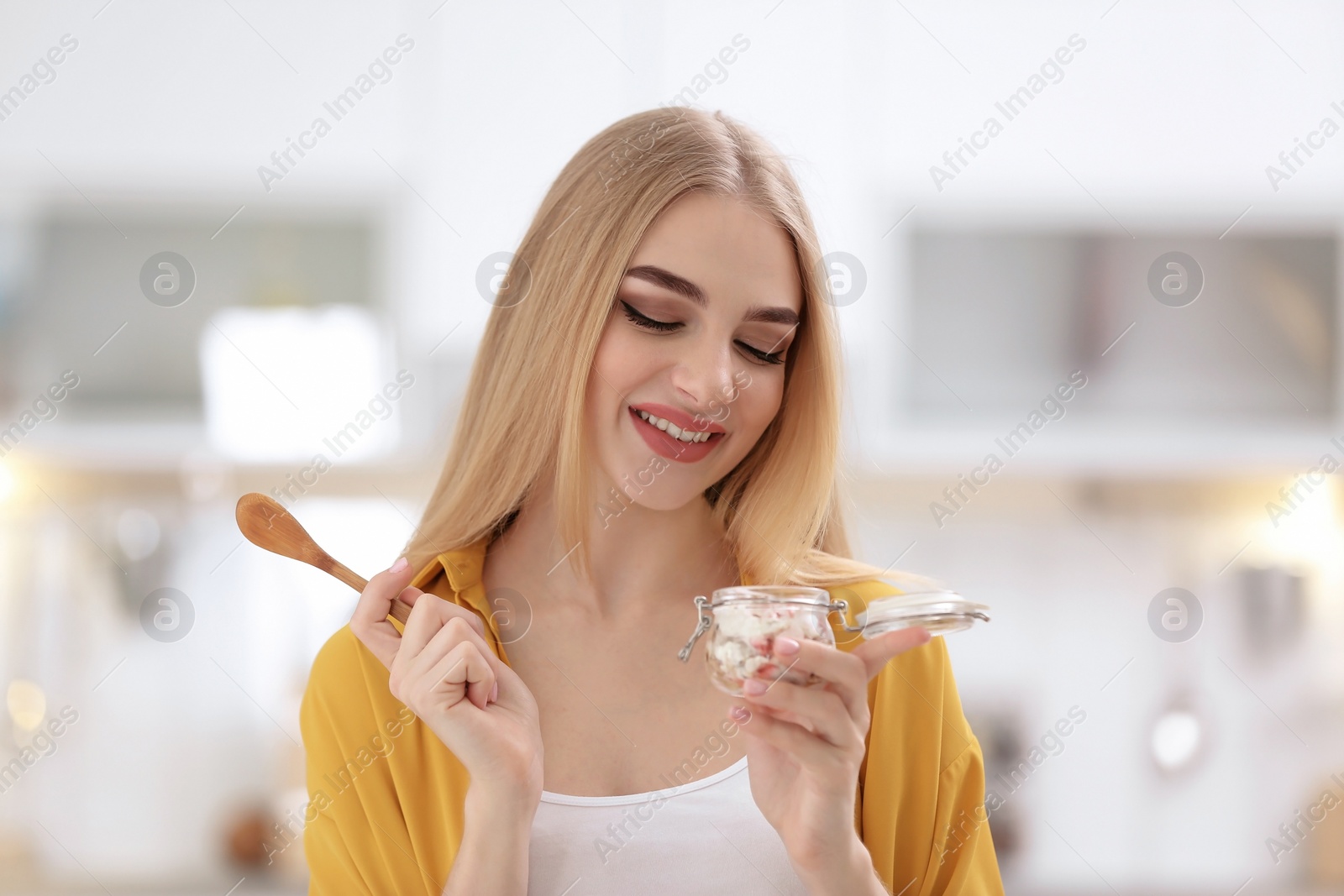 Photo of Young woman with yogurt on blurred background