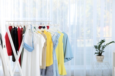 Racks with stylish clothes in light room