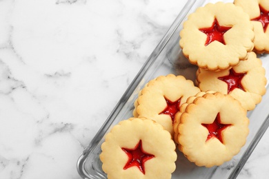 Traditional Christmas Linzer cookies with sweet jam in glass dish on marble background