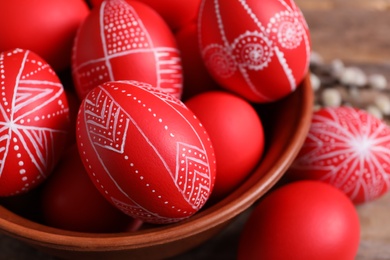 Wooden bowl with red painted Easter eggs on table, closeup