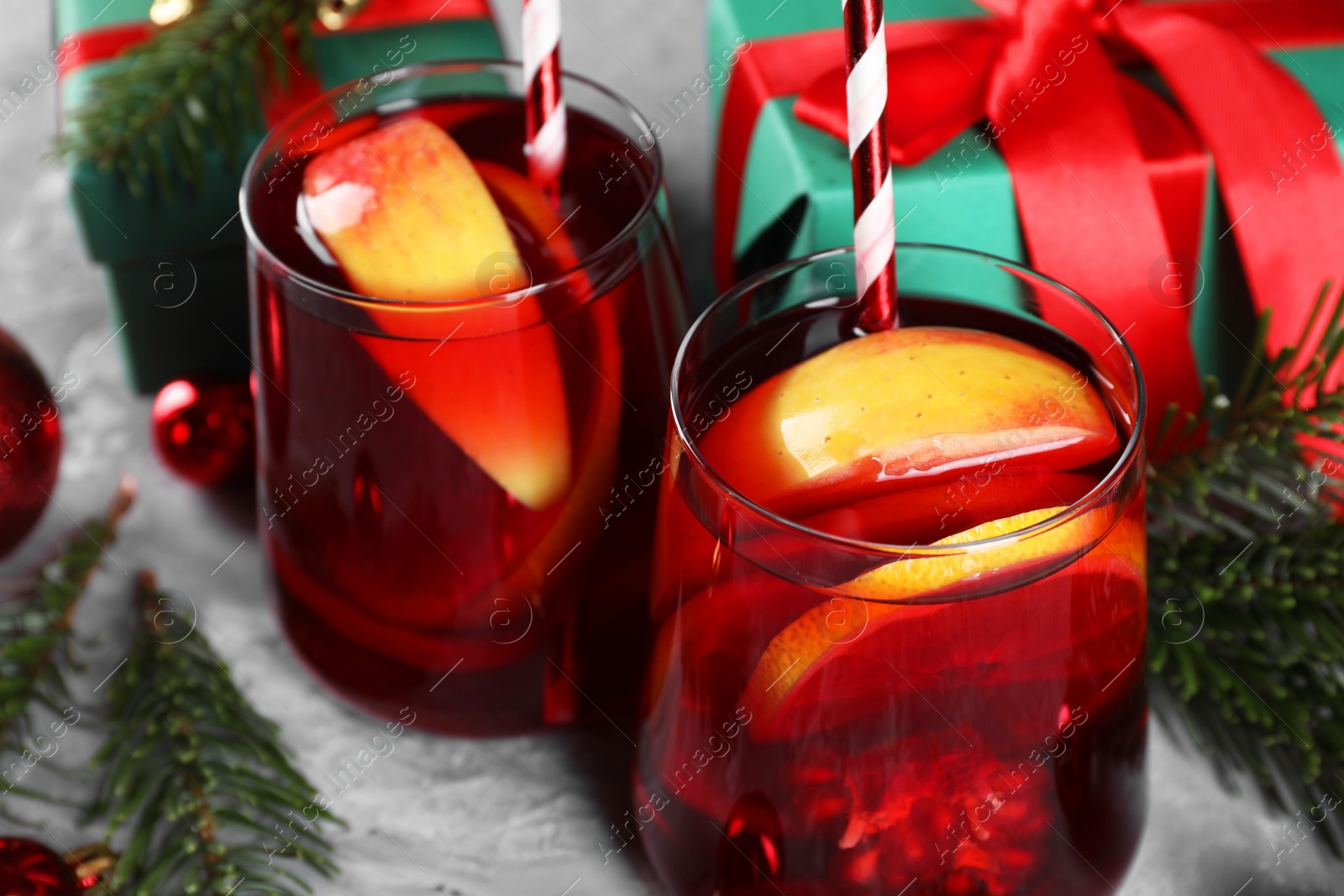 Photo of Delicious Sangria drink in glasses and Christmas decorations on grey table, closeup