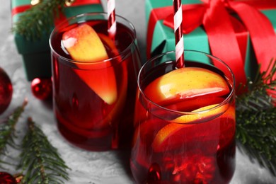 Photo of Delicious Sangria drink in glasses and Christmas decorations on grey table, closeup