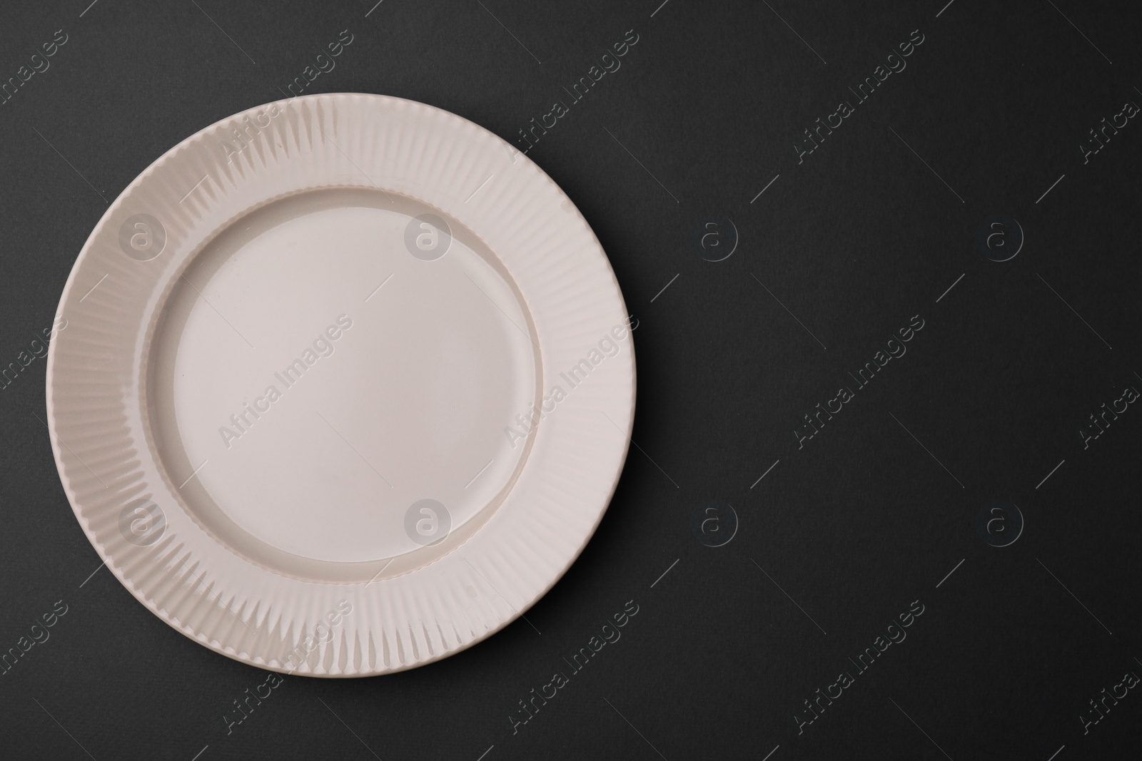 Photo of One clean plate on black background, top view. Space for text