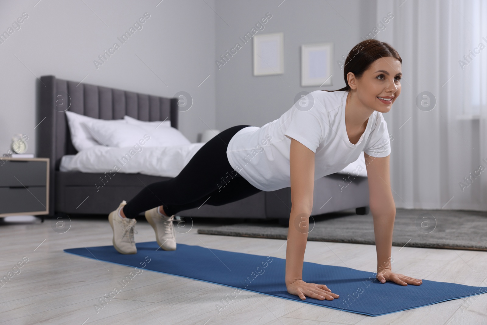 Photo of Happy woman doing plank exercise at home. Morning routine