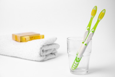 Light green toothbrush in glass holder on white background