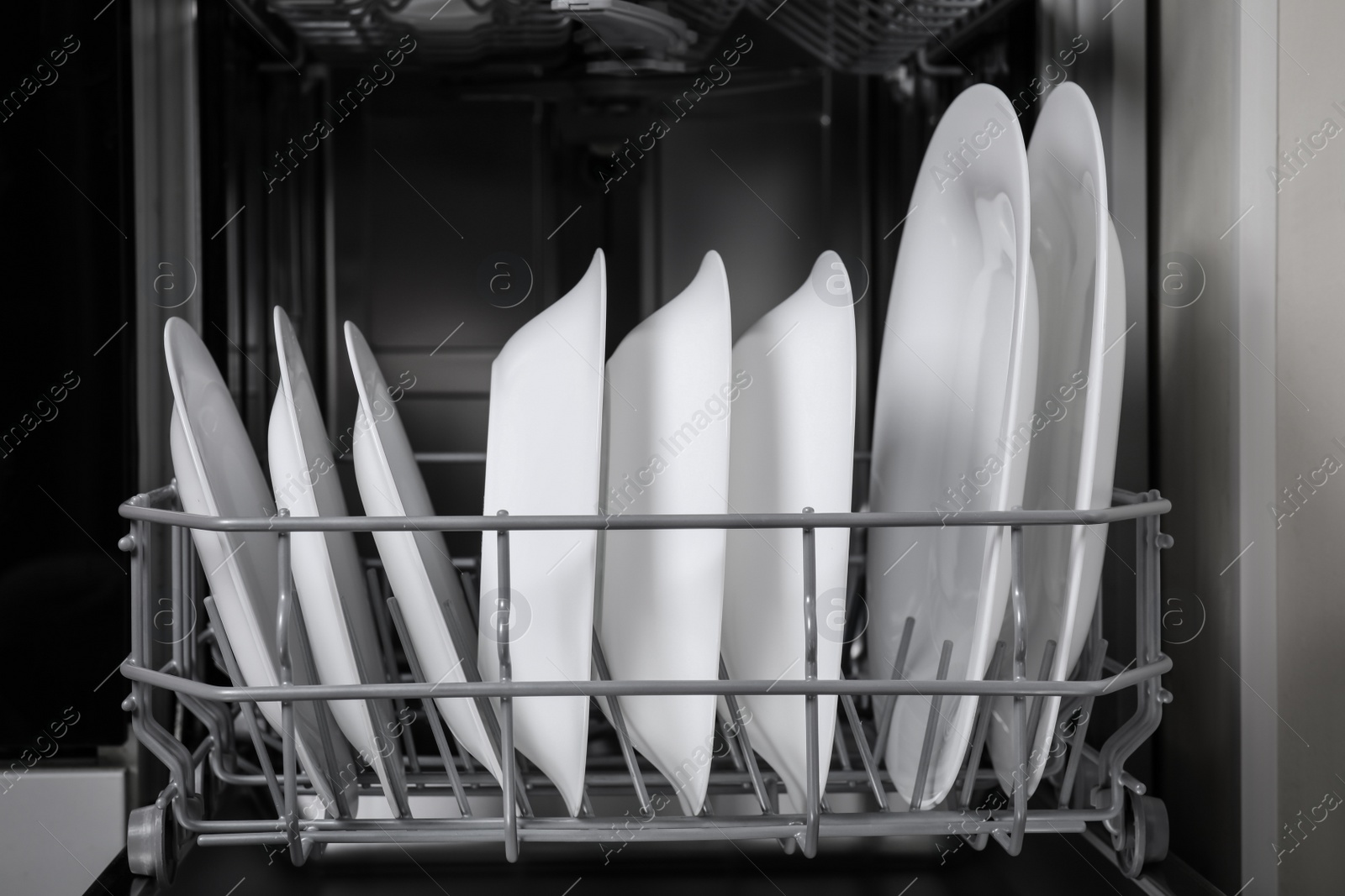 Photo of Open modern dishwasher with clean tableware, closeup