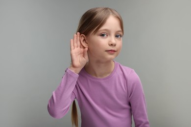 Little girl with hearing problem on grey background