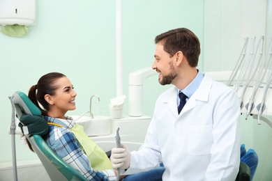 Photo of Professional dentist and happy patient in modern clinic