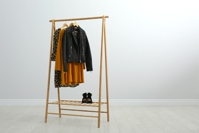 Wooden rack with stylish clothes in room. Space for text