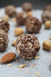 Delicious sweet chocolate candies and nuts on parchment paper, closeup