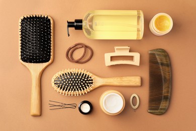 Photo of Flat lay composition with wooden hairbrushes and different cosmetic products on light brown background