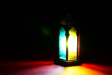 Photo of Decorative Arabic lantern on table against dark background. Space for text