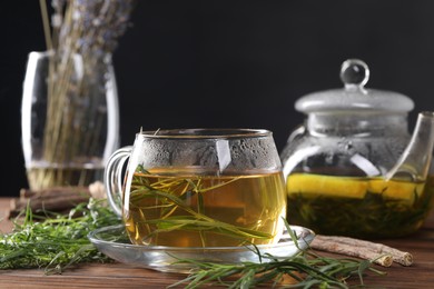 Homemade herbal tea and fresh tarragon leaves on wooden table