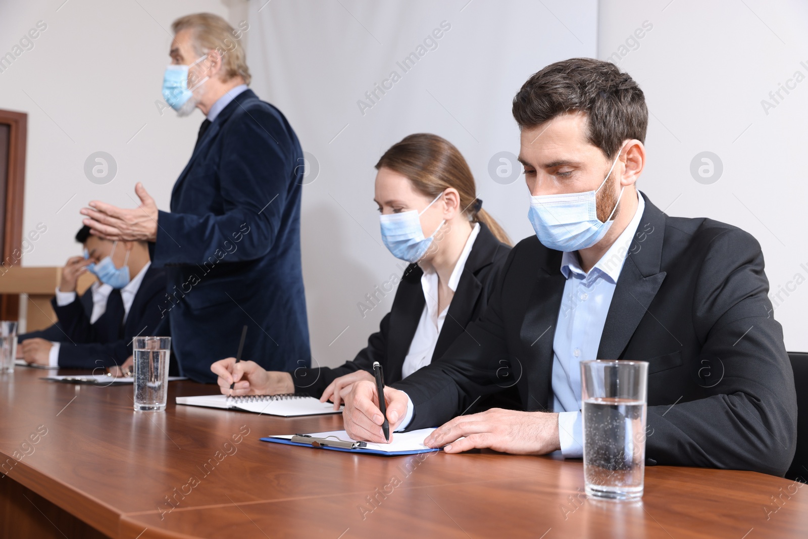 Photo of Business conference. People with protective masks listening to speaker report