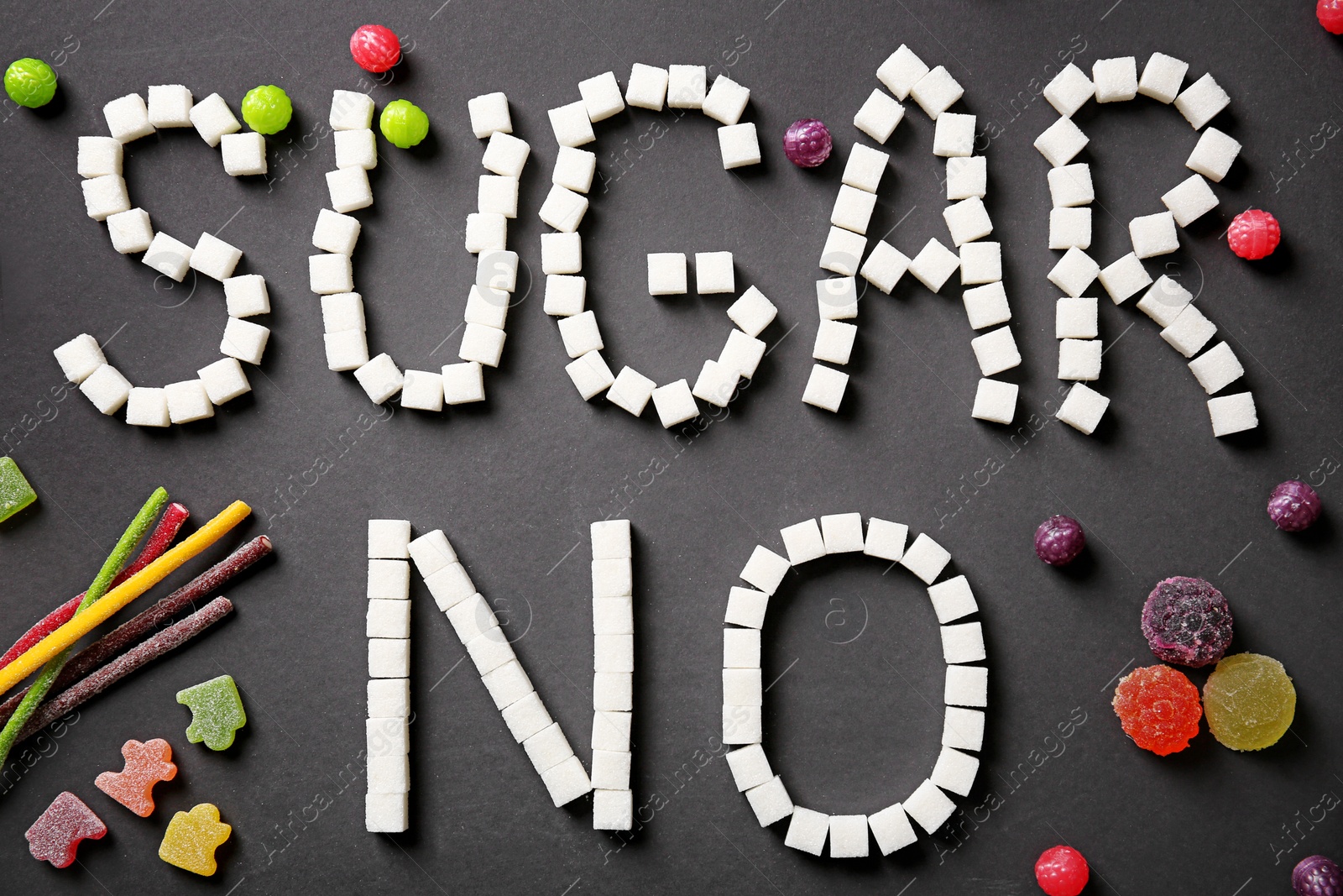 Photo of Composition with sweets and phrase NO SUGAR on dark background