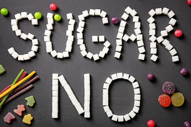 Composition with sweets and phrase NO SUGAR on dark background