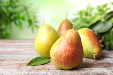 Photo of Heap of ripe juicy pears on brown wooden table against blurred background. Space for text