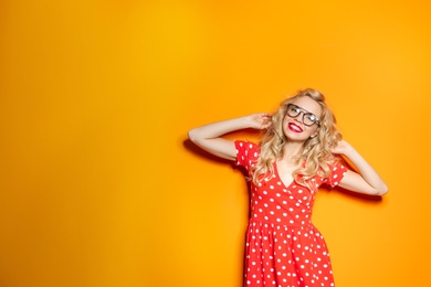 Photo of Stylish young woman with glasses posing on color background