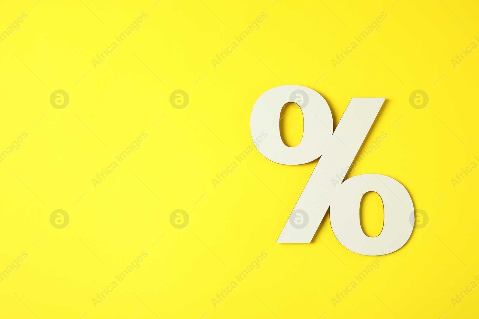 Photo of White percent sign on yellow background, top view. Space for text