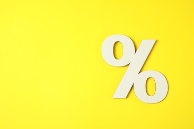 Photo of White percent sign on yellow background, top view. Space for text