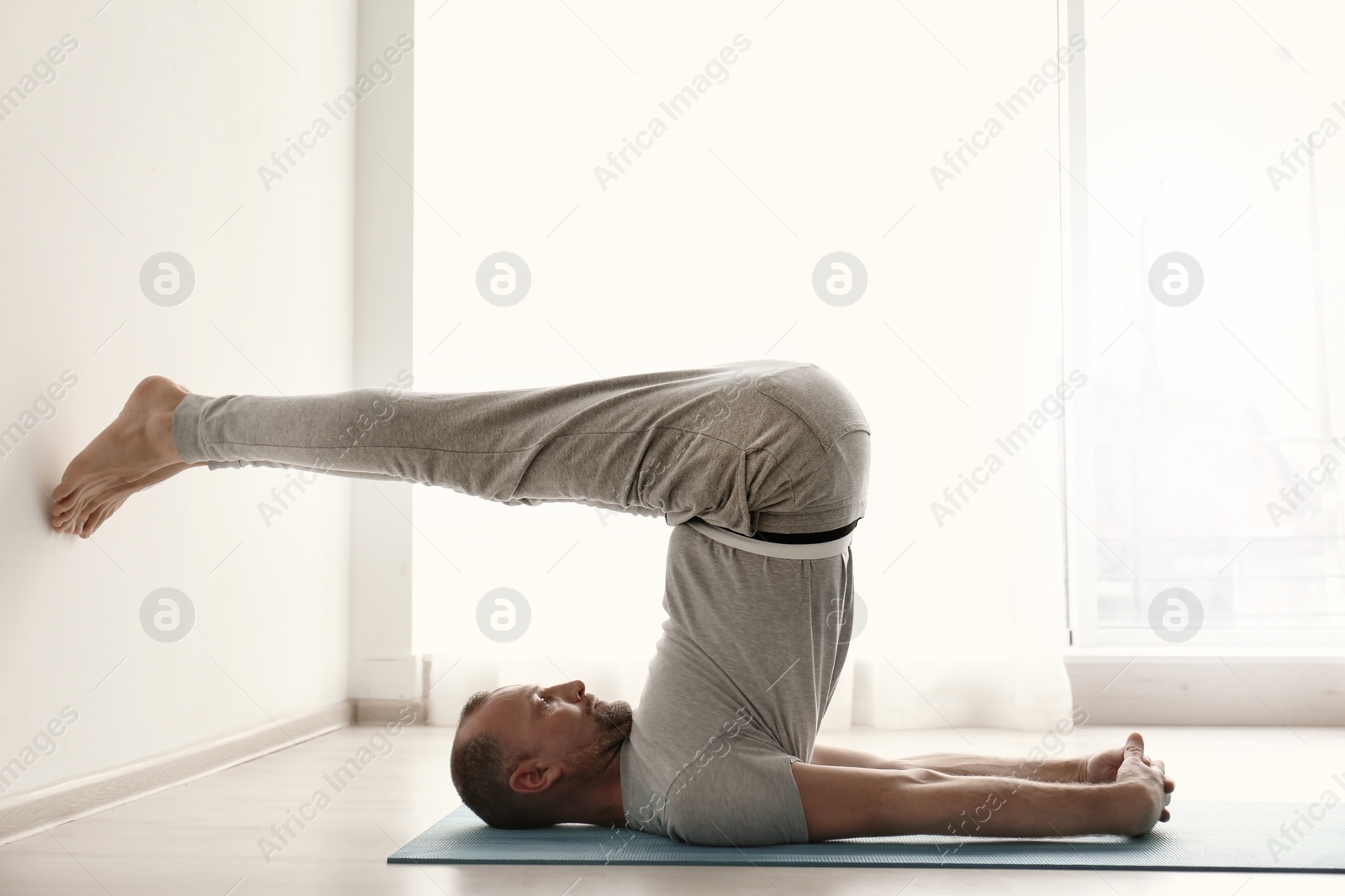 Photo of Sporty man practicing yoga indoors