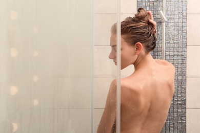 Beautiful young woman taking shower at home