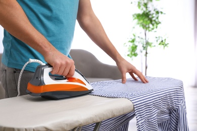 Man ironing shirt on board at home, closeup