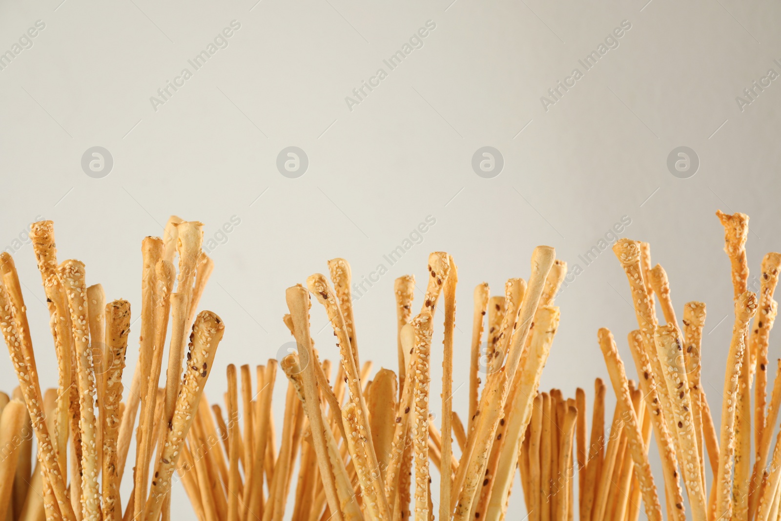Photo of Delicious grissini sticks on light background, closeup