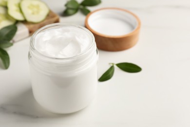 Photo of Glass jar of face cream on white marble table. Space for text