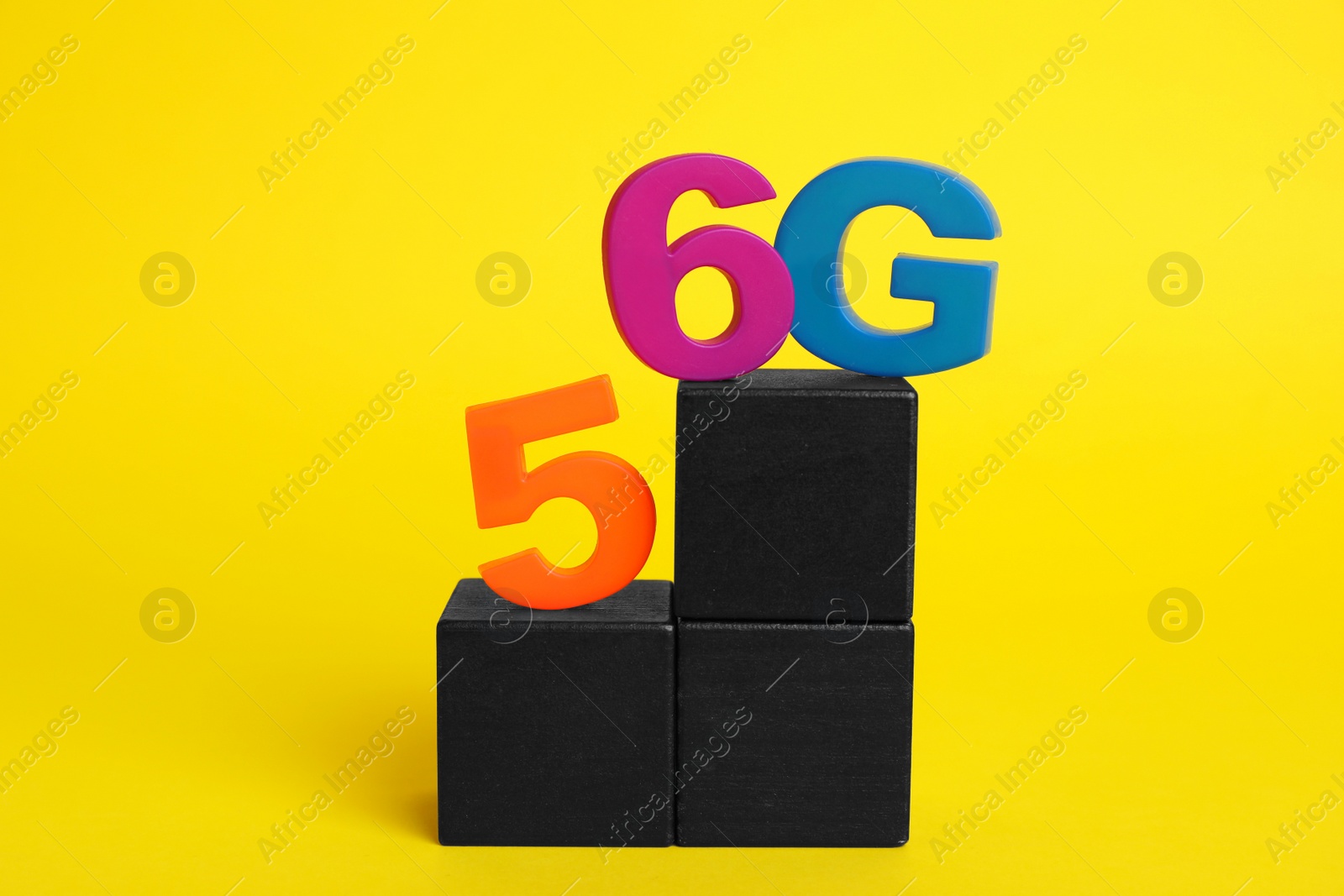 Photo of Internet concept. Black wooden cubes with 5 and 6G on yellow background