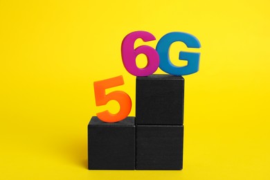 Internet concept. Black wooden cubes with 5 and 6G on yellow background