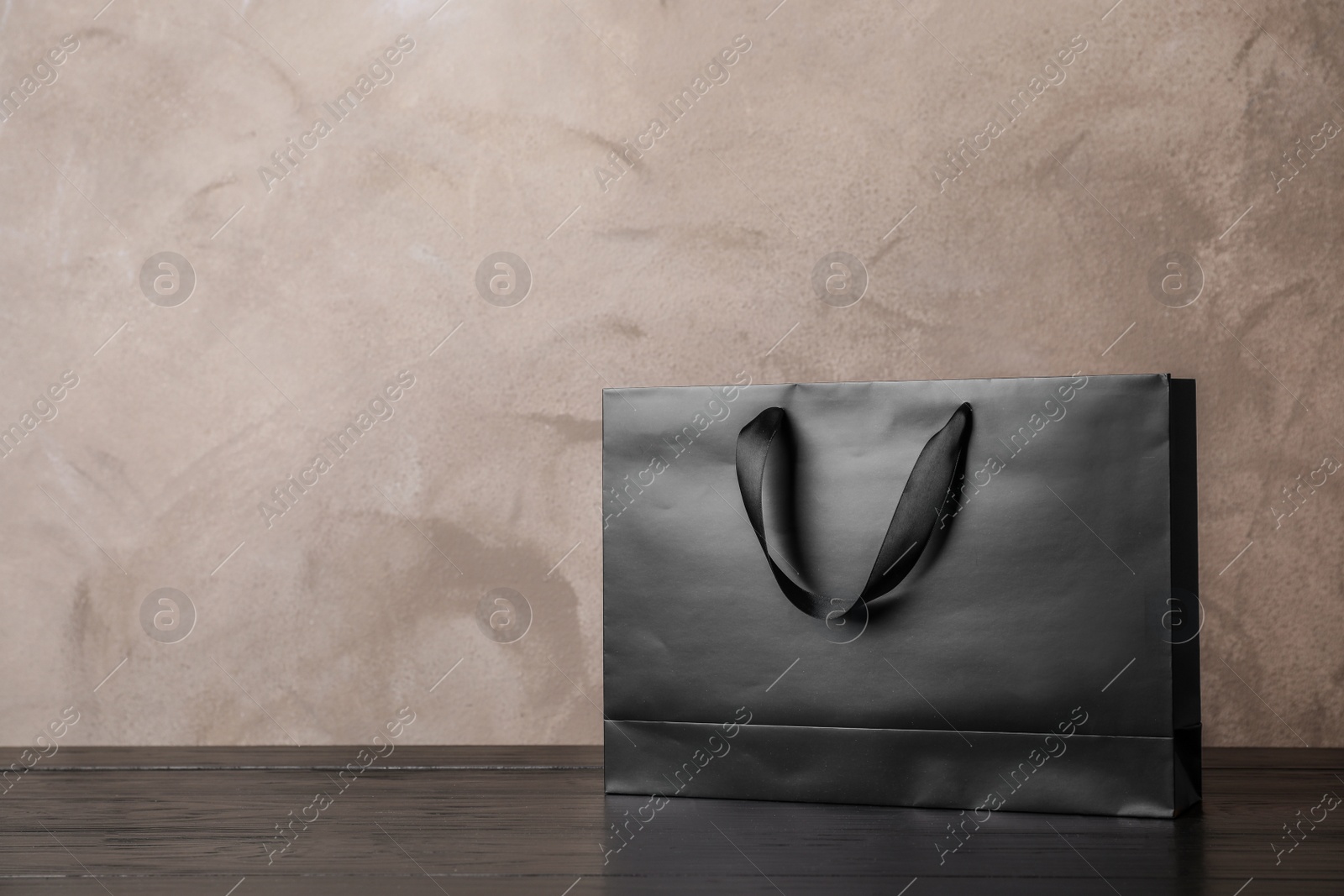 Photo of Paper shopping bag with handles on table against color wall. Mock up for design