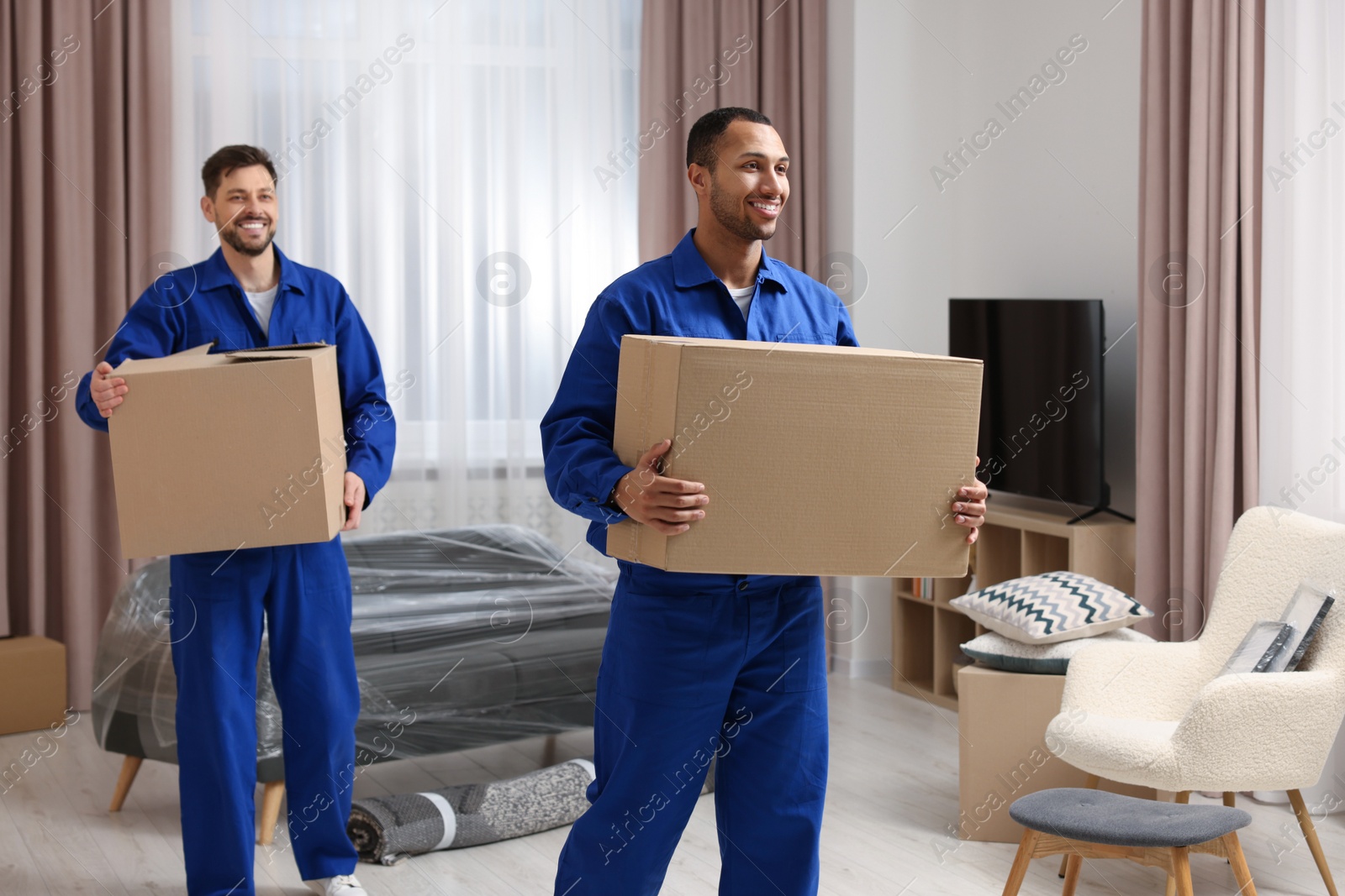 Photo of Male movers with cardboard boxes in new house