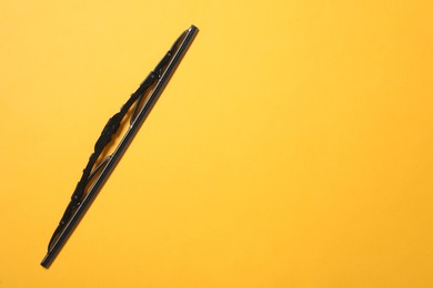 Car windshield wiper on yellow background, top view. Space for text