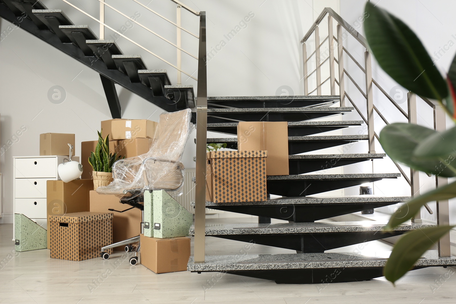 Photo of Cardboard boxes and packed chair near stairs in office. Moving day