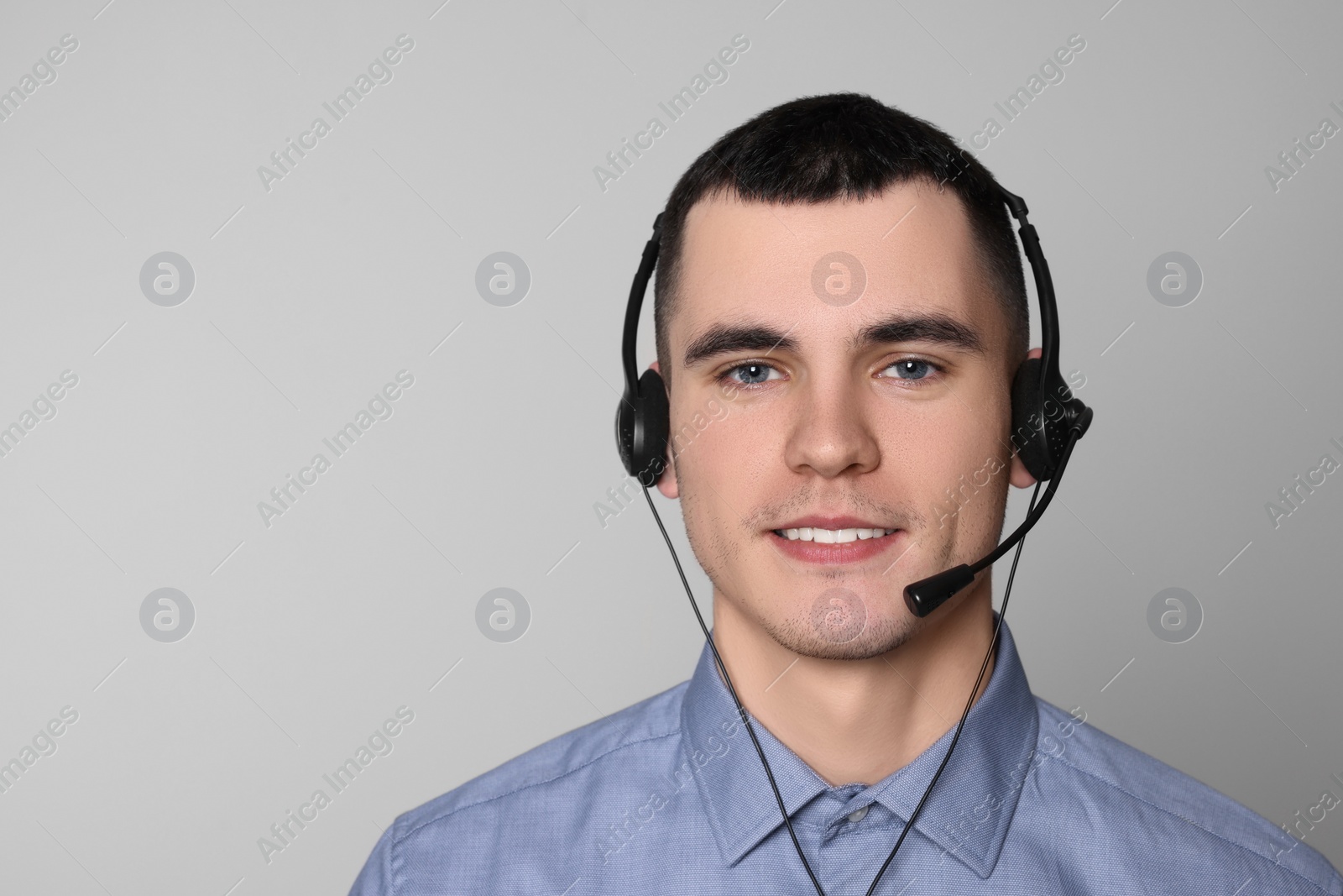 Photo of Hotline operator with headset on light grey background, space for text